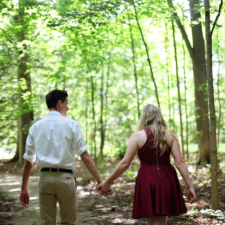 A couple walking hand in hand through woodland